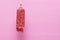 A piece of semi-smoked sausage hangs on a pink background