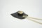 a piece of shushi with chopsticks in white background