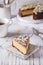 Piece Slice of Ð¡heesecake with Chocolate, Caramel, Peanut Paste, Nougat Layered Cake on white table background