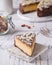 Piece Slice of Ð¡heesecake with Chocolate, Caramel, Peanut Paste, Nougat Layered Cake on white table background