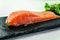 Piece of smoked fresh salmon with lettuce leaves on a slate Board