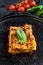 Piece of tasty hot lasagna.  Traditional italian food. Black background. Top view