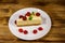 Piece of tasty New York cheesecake with raspberries in a white plate on wooden table