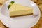 Piece of tasty sweet New York cheesecake in white plate on wooden table