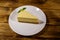 Piece of tasty sweet New York cheesecake in a white plate on wooden table