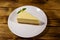 Piece of tasty sweet New York cheesecake in a white plate on wooden table