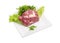 Piece of uncooked pork neck and greens on square dish