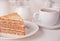 Piece of waffle cake and cup of coffee on the white table.