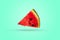 A piece of watermelon triangular in shape on a colored background. Ripe slice of fresh watermelon with red pulp and green peel