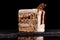 Piece of white cake with caramel and chocolate puffed rice on a black tray on black background