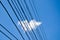 A piece of white floating cloud through the electric wires. Blue sky and floating clouds in the busy urban city