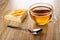 Piece of wicker pie with cottage cheese, spoon, cup with tea on wooden table