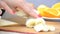 Pieces of banana cutting board chopped with a knife. Sliced orange and croissant on background