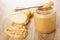 Pieces of bread, spoon with peanut butter on plastic jar with peanut butter, sandwich on table