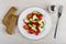 Pieces of bread, vegetable salad with mozzarella in plate, fork