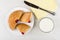 Pieces of bun with jam, knife, cup of milk, napkin