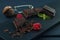 Pieces of chocolate, chocolate shavings, raspberry, mint and strainer with cocoa on dark wooden table