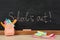 Pieces of color chalk and stationery near blackboard with text School`s Out. Summer holidays