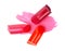 Pieces of color lipsticks on a pink lipstick smear, on white background