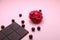 Pieces of dark chocolate bar and milk chocolate pearls and valentines rose on pink background, top view, copy space