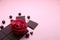 Pieces of dark chocolate bar and milk chocolate pearls and valentines rose on pink background, top view, copy space