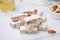 Pieces of delicious nutty nougat on white table, closeup