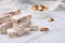 Pieces of delicious nutty nougat on white table, closeup