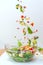 Pieces of fresh vegetables falling down into glass bowl creating healthy salad.