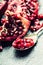 Pieces and grains of ripe pomegranate. Pomegranate seeds. Part of pomegranate fruit on granite board and antique spoon.