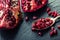 Pieces and grains of ripe pomegranate. Pomegranate seeds. Part of pomegranate fruit on granite board and antique spoon.