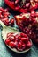 Pieces and grains of ripe pomegranate. Pomegranate seeds. Part of pomegranate fruit on granite board and antique spoon.