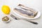 Pieces of herring in dish, lemon, bowl with condiment, fork