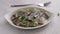 Pieces of herring fillet are sprinkled with green onions on a white plate. Salted sea fish, a traditional cold appetizer.