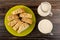 Pieces of horn-shaped buns in plate, pitcher with milk, cup with fermented baked milk on wooden table. Top view