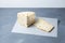 Pieces Italian Caciotta cheese with black peppercorns on grey table, selective focus