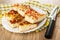 Pieces of khachapuri with tomato and basil in dish on napkin, knife  on wooden table