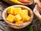 Pieces of mango fruit in a wooden bowl.