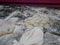 Pieces of massaged dough mixed with black sesame seeds on a table getting ready to be deep fried to make Chinese bread