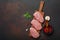 Pieces of raw pork steak with basil, garlic, pepper, salt and spice mortar on cutting board and rusty brown background with space