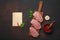 Pieces of raw pork steak with basil, garlic, pepper, salt and spice mortar and piece of paper on cutting board and rusty brown