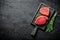 Pieces of raw tuna on a cutting Board with a bunch of rosemary