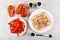 Pieces of red pepper in plates, salt, pepper shakers, chicken aspic in plate, fork on table. Top view