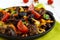 Pieces of roast duck, goose meat, liver, heart with vegetables onion, carrot, tomato, with spices on a round cast-iron frying