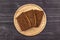 Pieces of rye flour black bread on a wooden serving plate and black rustic background