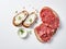 Pieces of salami on a rectangular piece of bread spread with butter. White background