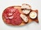 Pieces of salami on a rectangular piece of bread spread with butter. White background