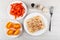 Pieces of tomatoes and pepper in plates, chicken aspic in plate, fork, garlic on table. Top view