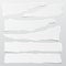 Pieces of torn white note, notebook paper strips stuck on gray background