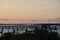 Pier, boats and bridge in silhouette against a pink sky as sunset.