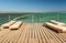 Pier with chaise longues in the sea in resort.